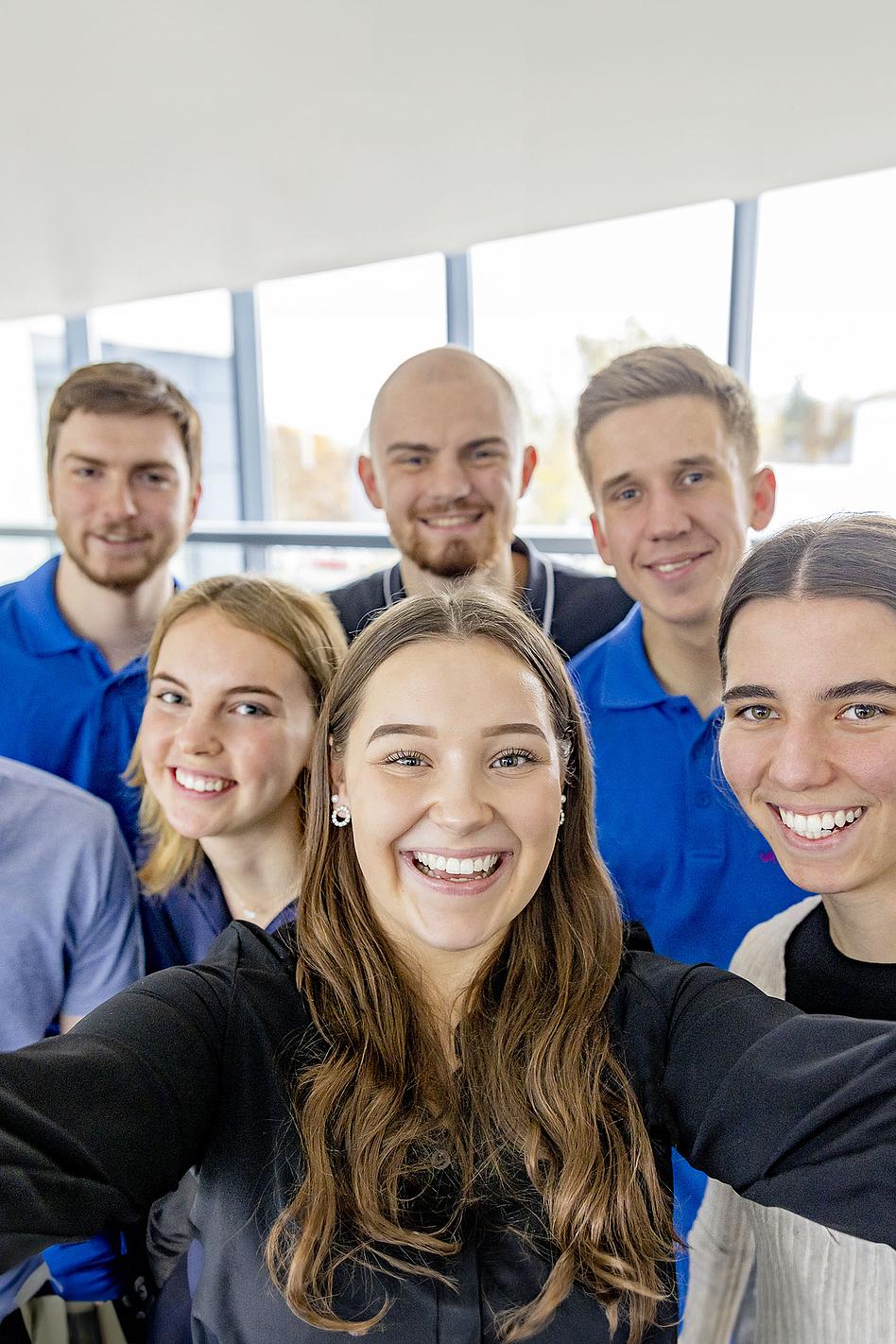 Eine Gruppe junger, lächelnder Menschen machen ein Selfie.