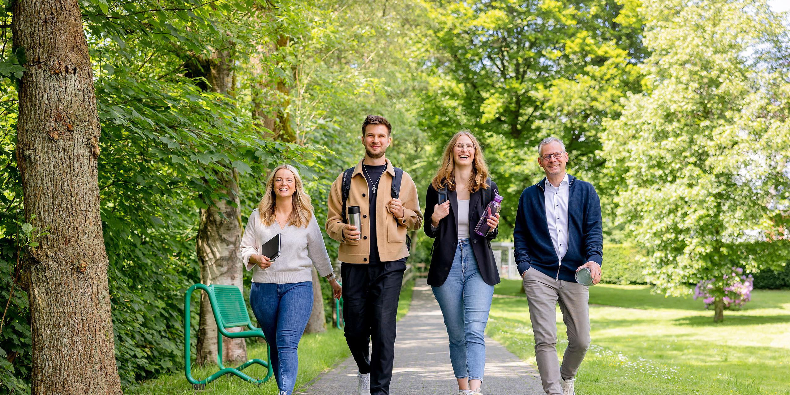 Zwei Frauen und zwei Männer mit fröhlichen Gesichtern während eines Spaziergangs durch den Park.