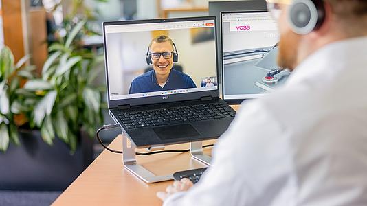 VOSS Mitarbeiter am Laptop in einem Video-Call.