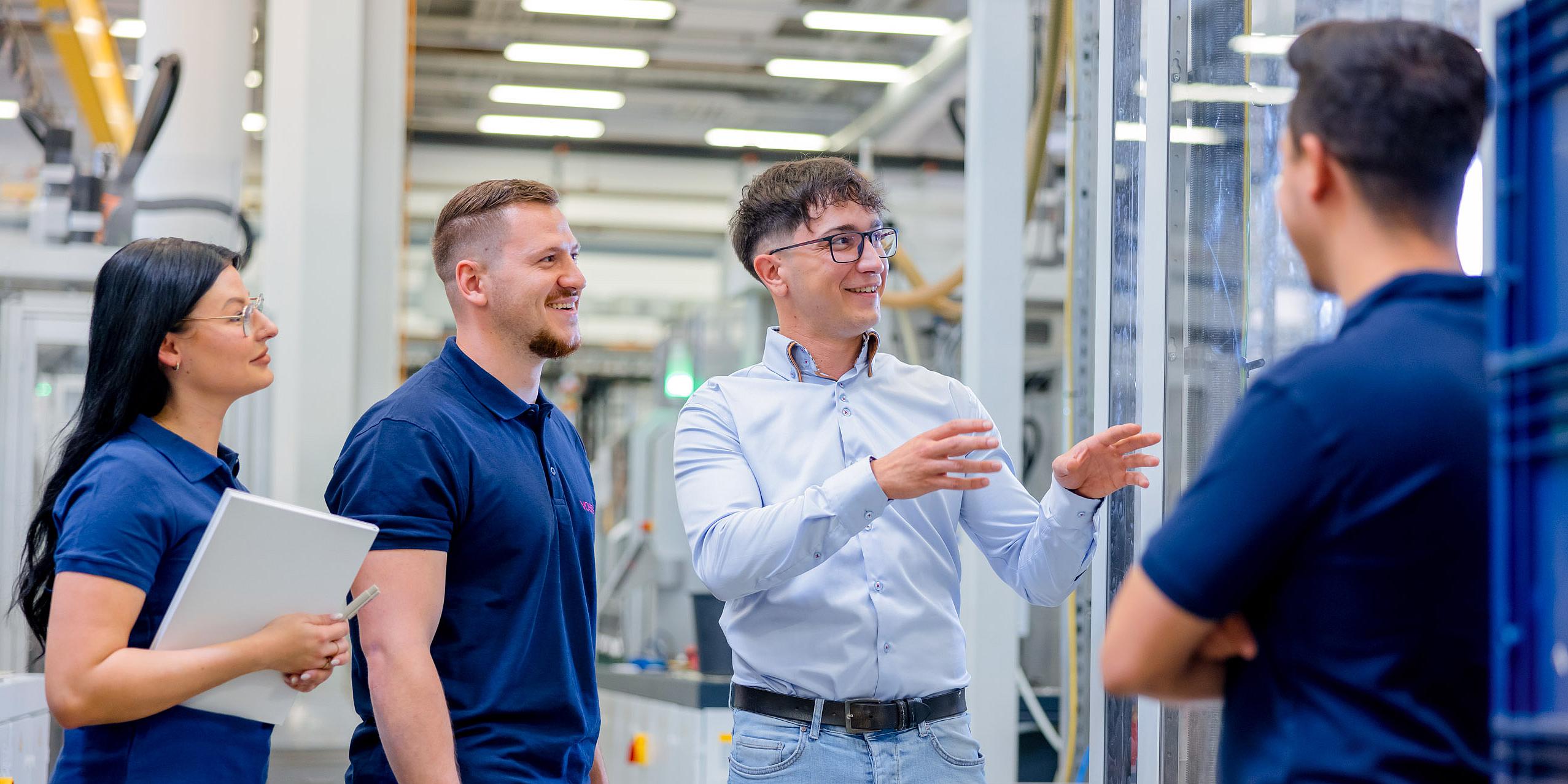 Vier Personen in einer Produktionshalle.