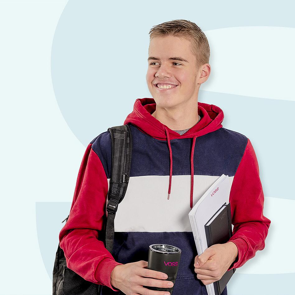 Ein lächelnder junger Mann mit einem Rucksack über der Schulter, einem VOSS Kaffeebecher und Schreibblock in der Hand.