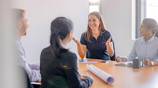 Vier VOSS Mitarbeiter:innen sitzen an einem Tisch.